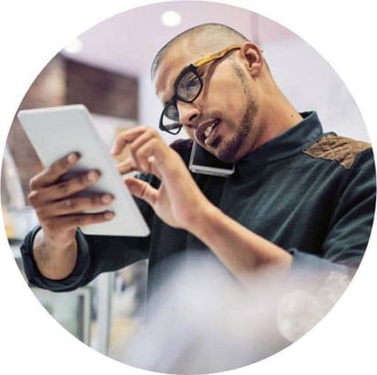 Restaurant worker holding a phone to his ear while using a tablet