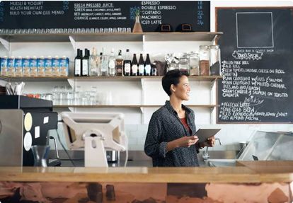 Restaurant worker standing behind the counter while holding a tablet