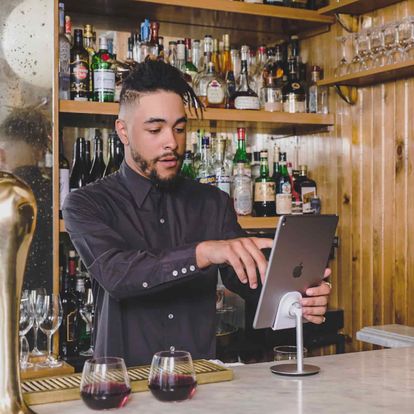 A male bartender using a restaurant POS system on an iPad