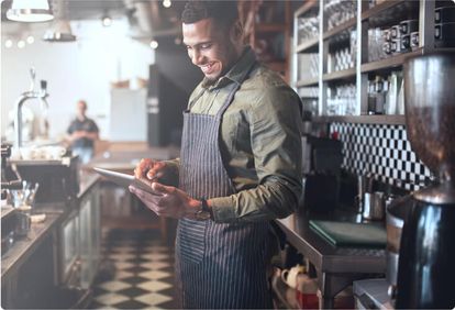 Server tending to table full of customers while holding a tablet to record orders