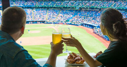 Friends raise a glass overlooking a baseball field