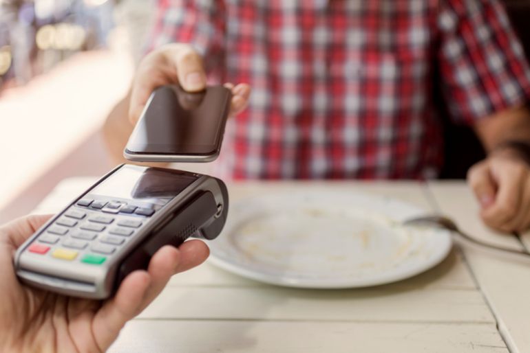 A. man making a payment for food at a restaurant with his smartphone