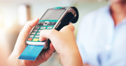 Customer holding a payment terminal with a chip card inserted at the bottom