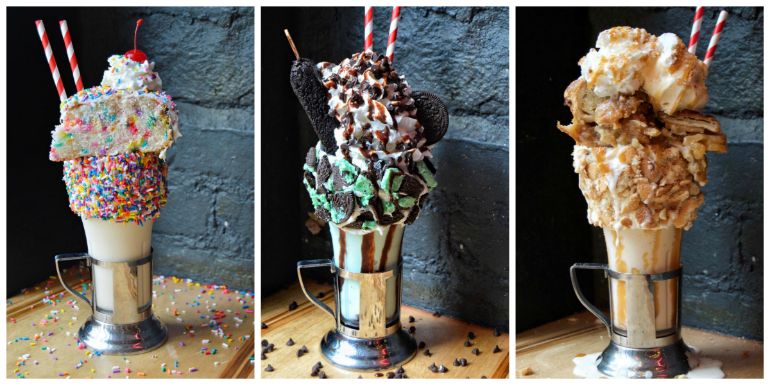 three milkshakes piled high with cake, cookies and other toppings