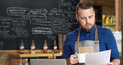 Cafe owner looks over financial data with a cup of coffee