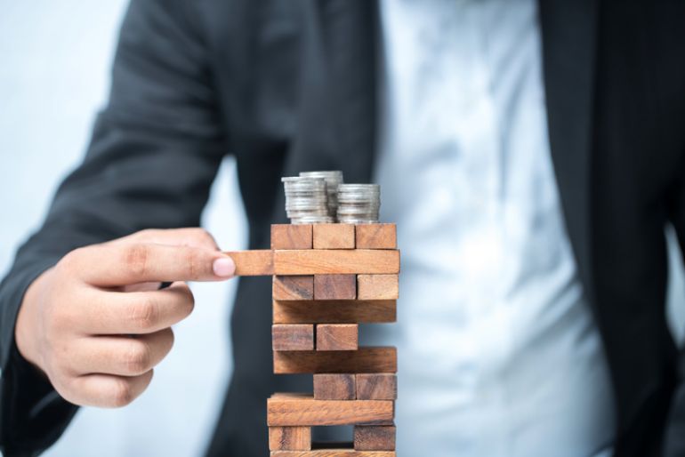 Jenga being played with some coins stacked on top