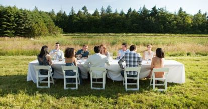 Diners seated around a table in a green pasture