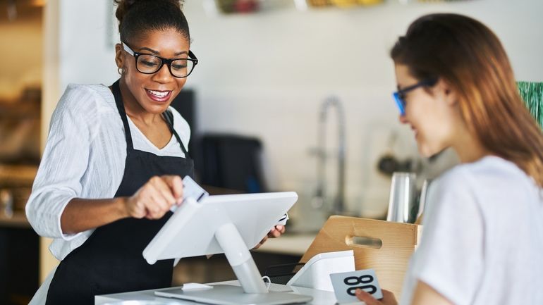 Waitress swiping customers bank card on POS terminal at restaurant