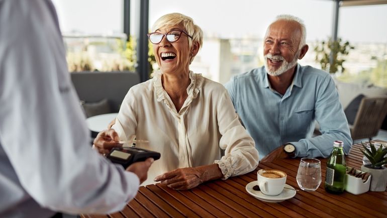 Older couple using contactless payment at a restaurant