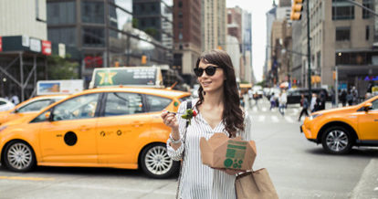 Woman eating a salad from a takeout box on the streets of NYC