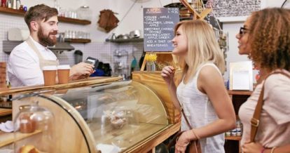 Two women in checkout line talking to employee behind the counter