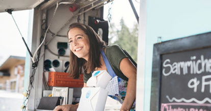Food truck owner leaning out service window smiling
