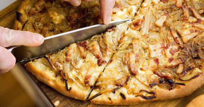 A person cutting a slice out of a pie from La Tarte Flambée