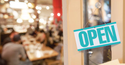 Open sign hanging at the door of a busy restaurant