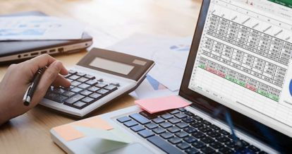 person working at a desk with a spreadsheet and calculator