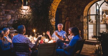 Table of friends dining outdoors by candlelight