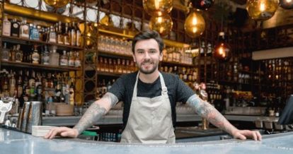 Bar manager standing behind bar