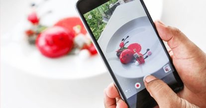 Smartphone photographing a beautifully plated dish of food
