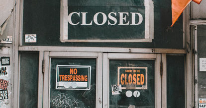 Restaurant storefront boarded up with closed signs