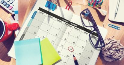 A calendar, glasses, post-its, and other office supplies on a table