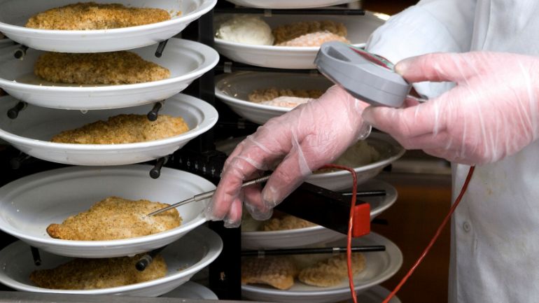 Restaurant chef checking temperature of cooked chicken using digital thermometer