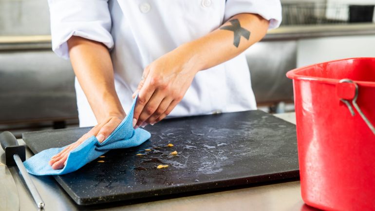 Restaurant chef wiping cutting board after food prep
