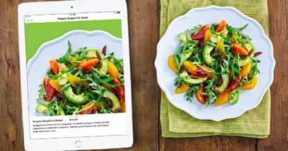 A salad dish next to an ipad with a picture of the same salad dish