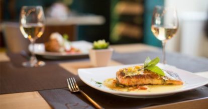 Two plates of fish with wine glasses