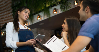 Server using a tablet to take guests' orders at a restaurant.