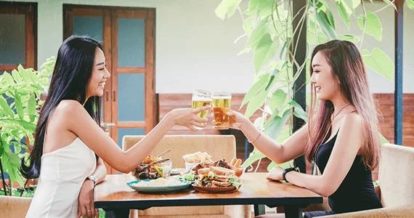 Two friends raising a glass and enjoying a meal on a patio