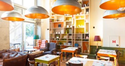 Compact interior of small restaurant space with bold coloured furniture and large ceiling lights