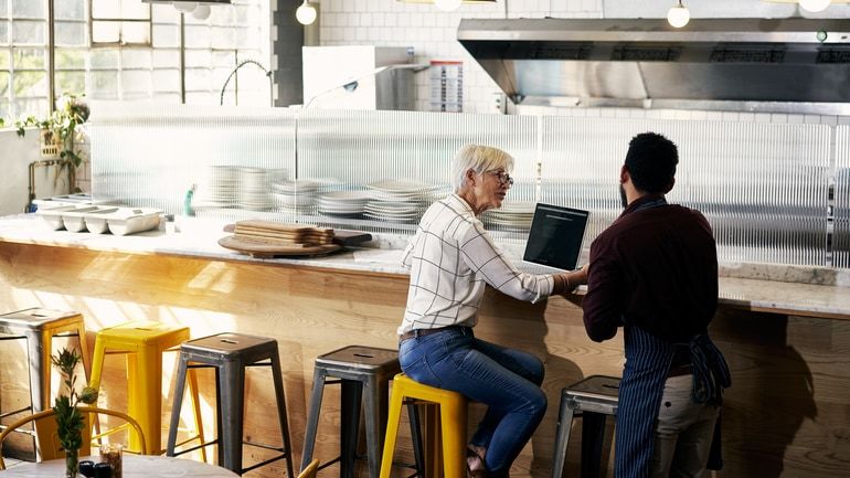 Restaurant staff using a laptop on a counter