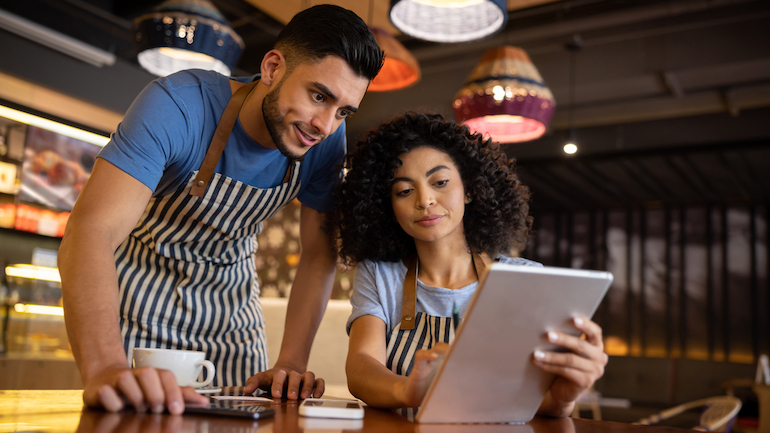 Two restaurant workers looking at a tablet.