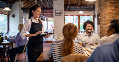 Smiling server using a tablet to take guests orders.