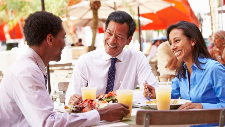 Coworkers having lunch at a restaurant and laughing together