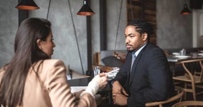 A man and a woman sitting talking in a empty restaurant.