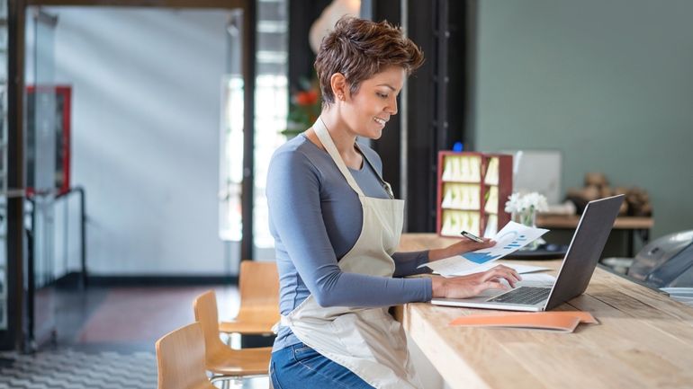 woman in an apron on a laptop looking at profit margins
