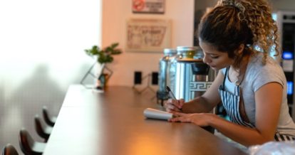 Restaurant worker behind counter writing in a note pad