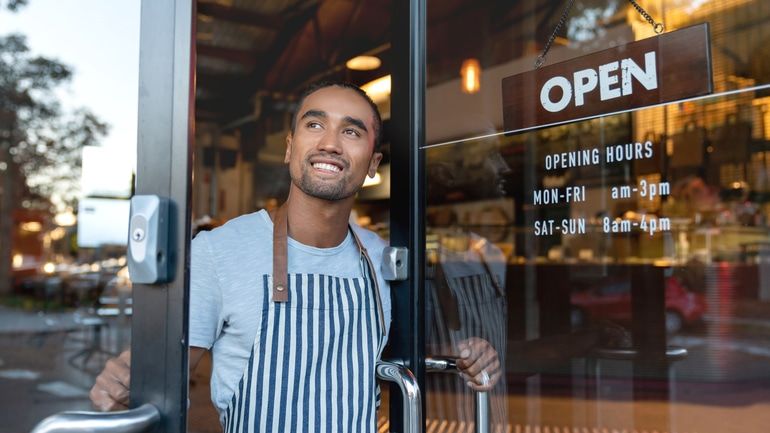 Waiter opening the doors of a cafe with an open sign