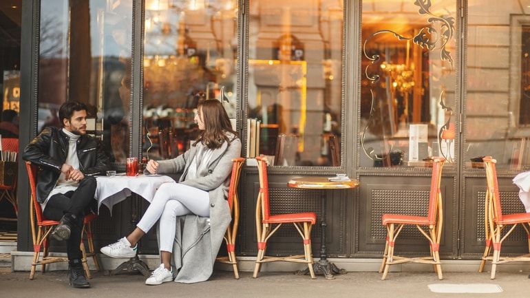 A woman and man dining outside of a cafe