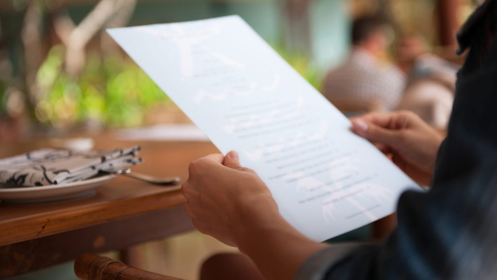 Customer reading a menu at a restaurant.