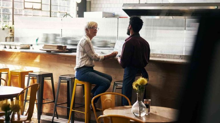 Two restaurant owners discussing paperwork at the bar.