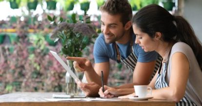 2 restaurant workers doing financials on iPad at a restaurant table