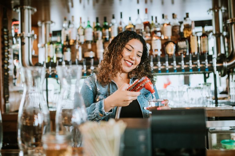 Female bartender mixing a well drink behind the bar