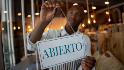 man hangs open sign restaurant window