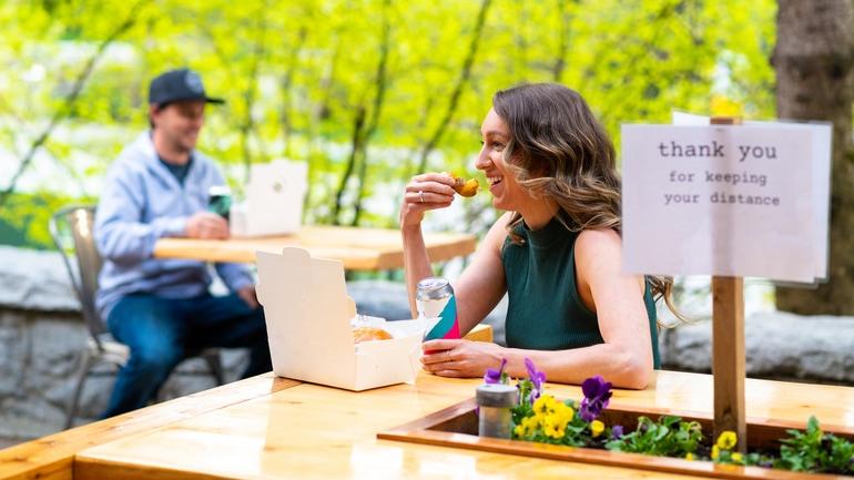 Groups of women dining at two cafe tables spaced far apart