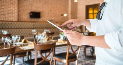 Restaurant employee on an iPad standing in a restaurant