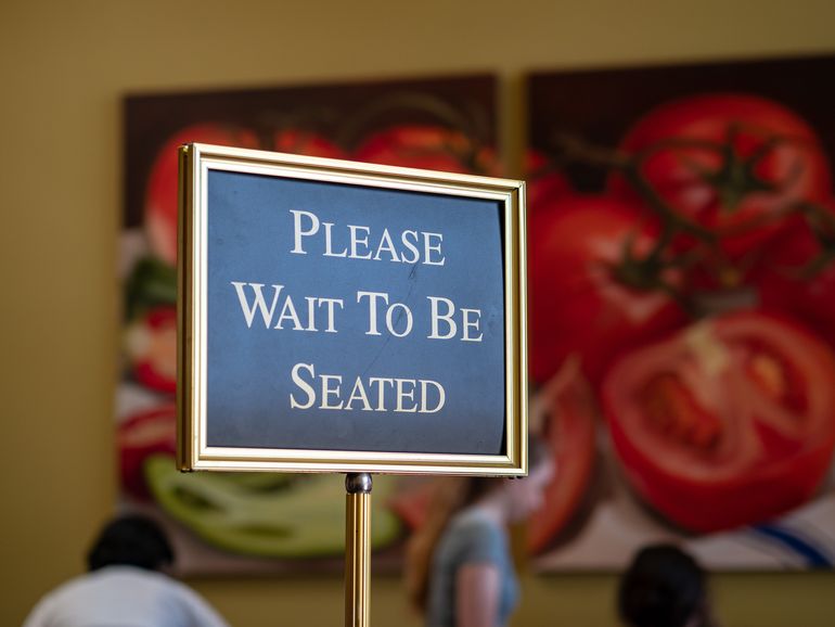  A sign at a restaurant with reservations telling guests to wait to be seated