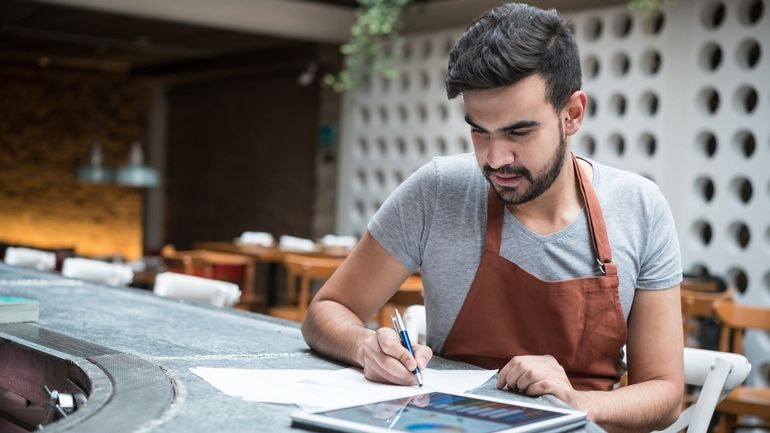 Restaurant working using a tablet to manage finances, menu, and inventory