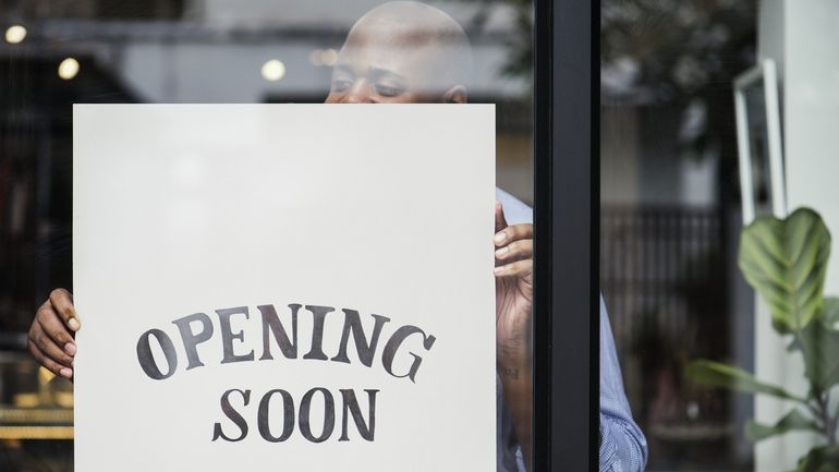 Man hanging an "opening soon" sign in a restaurant